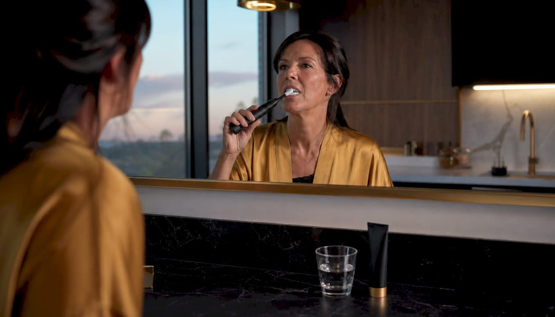 Woman brushing teeth in bathroom mirror