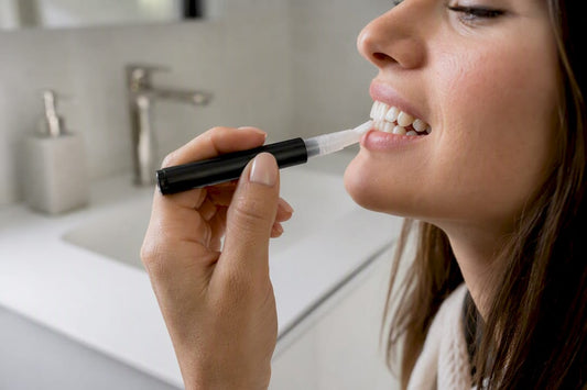 Close-up applying whitening pen to front teeth