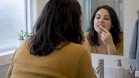 Woman examining smile after whitening treatment